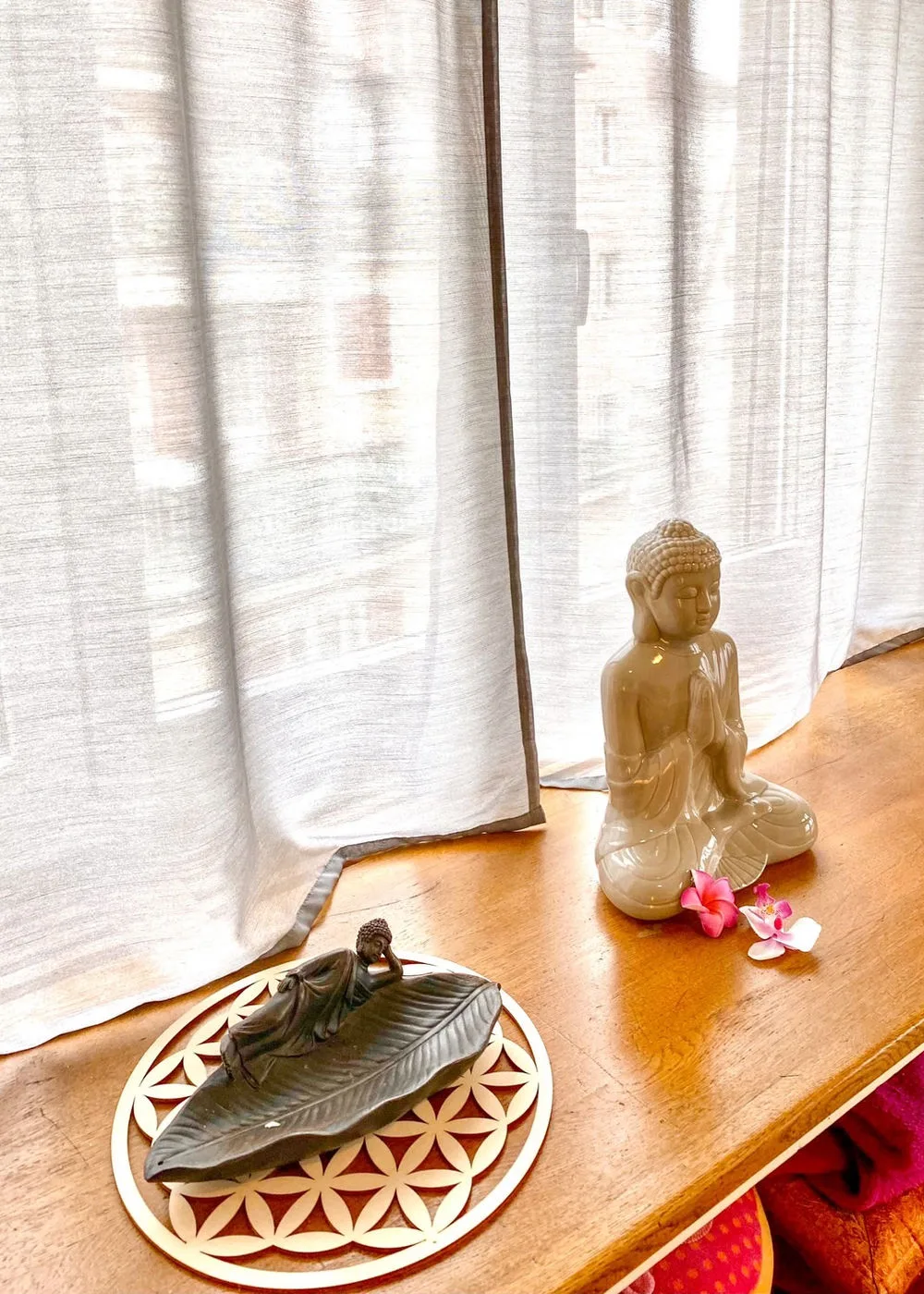 Buddha-Figur und Blumen auf dem Fensterbrett im Praxisraum